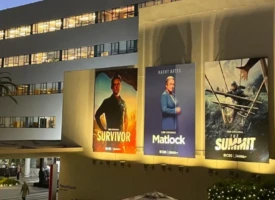 Photo of a Hollywood studio wall covered with television and movie posters advertising a variety of productions.
