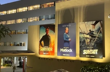Photo of a Hollywood studio wall covered with television and movie posters advertising a variety of productions.