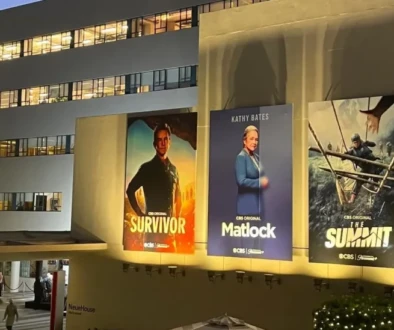 Photo of a Hollywood studio wall covered with television and movie posters advertising a variety of productions.