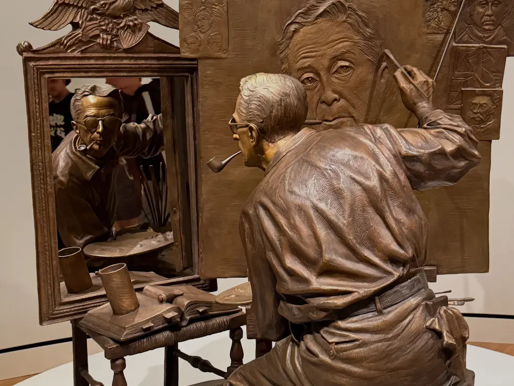 Norman Rockwell self-portrait showing the artist painting himself while looking into a mirror, displayed at the Lucas Museum of Narrative Art.